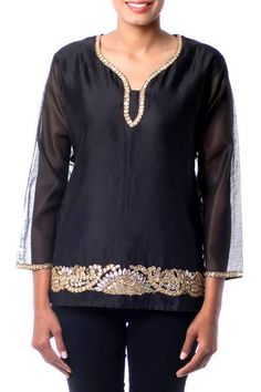 A shimmering black cotton and silk blend becomes a beautiful blouse by Isha Jain. Intricate gota embroidery combines with beads and sequins to surround the sleeves and neckline while a wide band trims the front hem. Similar to applique gota embroidery involves adding a different fabric to the background to create new textures. Elegant Embroidered Top For Diwali, Festive Embellished Chanderi Blouse Piece, Bollywood Style Embroidered Kurta For Festivals, Bollywood Style Festival Kurta With Embroidered Neckline, Festive Designer Embellished Embroidered Top, Long Sleeve Chanderi Kurta With Embroidered Neckline, Chanderi Kurta With Embroidered Neckline And Long Sleeves, Festive Sequined Chanderi Blouse Piece, Diwali Embellished Long Sleeve Blouse Piece