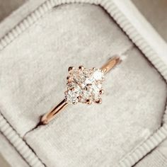 an engagement ring with three diamonds in it on top of a white velvet box,