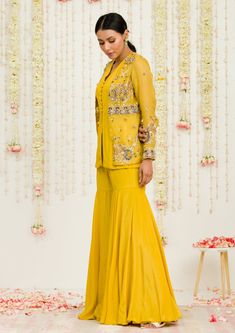 Editor's Note Mustard Hand Embroidered Jacket With Matching Peplum And Sharara In Crepe Fabric: Crepe, Organaza Color: Mustard Care: Dry Clean Only About the Designer Sanya Gulati's designs are inspired by the Indian bridesmaids, pastel easy hues & seasonal trends, her designs are a mix of modern, contemporary embroideries with traditional silhouettes thus creating our signature asymmetric checks embroideries amalgamated with floral thread work, through her designs, the designer aims to enhance Long Sleeve Floral Embroidered Sharara For Spring, Spring Long Sleeve Sharara With Floral Embroidery, Spring Long Sleeve Floral Embroidered Sharara, Embellished Long Sleeve Nehru Jacket For Designer Wear, Eid Embellished Long Sleeve Bandhgala, Floral Embroidered Sharara For Eid, Embellished Yellow Sets For Spring, Spring Embellished Yellow Sets, Embellished Long Sleeve Nehru Jacket For Festive Occasions