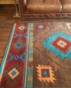 a brown leather couch sitting next to a rug on top of a wooden floor in a living room