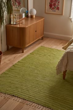 a green rug on the floor in a bedroom next to a wooden dresser and mirror