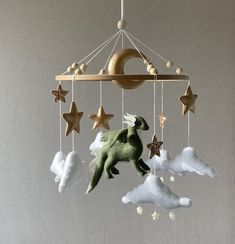 a mobile with stars and a stuffed animal hanging from it's sides, in the shape of a dinosaur