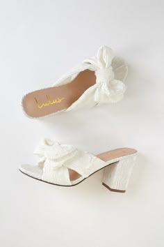 two pairs of white shoes with bows on them