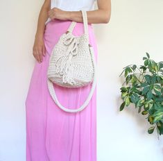 a woman wearing a pink skirt holding a white purse