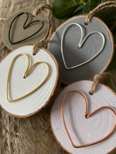 three heart shaped ornaments hanging from twine on wooden slices with string attached to them