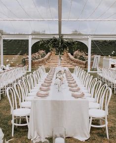 a long table is set up with white chairs and tables for an outdoor wedding reception