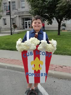 a young boy is holding a popcorn box costume