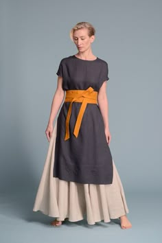 a woman is wearing a dress with an orange sash around her waist and the bottom part of her body