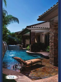 a pool with a waterfall and lounge chair next to it in front of a house