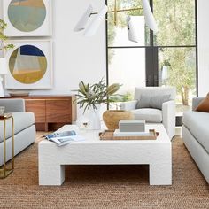 a living room with couches, tables and pictures hanging on the wall above them