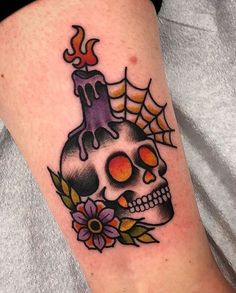 a skull with a candle and flowers on it's leg is seen in this tattoo design