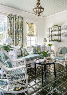 a living room filled with white wicker furniture and lots of green pillows on top of it