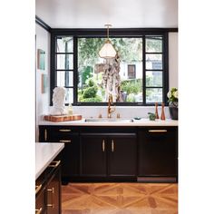 a kitchen with black cabinets and white counter tops is pictured in this image, there are two lamps hanging over the sink