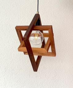 a wooden light fixture hanging from the ceiling with a glass bulb in it's center