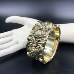 In very NICE condition with minimal wear - a vintage SIGNED (see Photo 9) Whiting & Davis repoussé hinged bangle bracelet with a safety chain and box clasp.  This was a find from the estate sale of a local couple who loved fine antiques and jewelry. The bracelet most likely dates to the 1960s/1970s. I have described the bracelet as being "gold tone" but the gold tone is more prominent on the INSIDE of the bracelet.  The "gold" finish on the exterior is more SUBTLE and at times looks like a cross between gold and silver. The finish is lovely and the repoussé has what has been described in other listings as a "mesh" texture in places as well as a "fleur-de-lis" design. MEASUREMENTS: The bracelet has a width of 1.25 inches (see Photo 4).  The opening (when the bracelet is locked) measures 2-3 Antique Engraved Cuff Bracelet For Formal Occasions, Antique Adjustable Cuff Bracelet For Formal Occasions, Formal Bronze Bangle Jewelry, Antique Cuff Bracelet For Formal Occasions, Antique Bronze Bracelets For Formal Occasions, Vintage Hinged Bangle, Antique Gold Bangle For Formal Occasions, Adjustable Victorian Cuff Bracelet For Formal Occasions, Antique Gold Bangle Jewelry For Formal Occasions