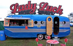 an old camper converted into a bar with chairs and tables in front of it