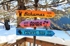 a wooden sign post with several different signs on it's sides in the snow