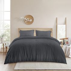 a bedroom with a large bed covered in dark gray linens