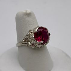 Gorgeous Floral Ruby Ring in Sterling Silver  * 4ct Ruby measures 10mm Round  * Solid Sterling Silver  * Size 7 - sizing available  Also available in 10k, 14k and 18k Gold - message me for current Gold pricing.    Hallmarked and Gift Ready!  This 4ct Ruby is Laboratory Grown. It is identical to natural in every way, including Chemistry, Composition & Hardness with flawless clarity & excellent color refraction.  TIMELESS, BEAUTIFUL & UNIQUE FINE ART JEWELRY! Classic Crystal Birthstone Ring For Formal Occasions, White Gold Ruby Jewelry, Silver Rings With Lab-created Ruby, Elegant Silver Ruby Ring With Round Stone, Silver Jewelry With Lab-created Ruby Center Stone, Silver Jewelry With Center Stone Lab-created Ruby, Heirloom Style Lab-created Ruby Round Cut Jewelry, Heirloom Lab-created Ruby Jewelry In Round Cut, Classic Silver Jewelry With Lab-created Ruby