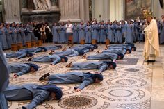 a group of men laying on the ground in front of a crowd of people wearing blue robes