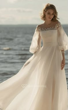 a woman in a white dress standing on the beach