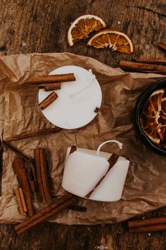 an orange slice and cinnamon sticks sit on wax paper next to some sliced oranges