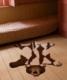 a brown and white animal rug on the floor next to a bed