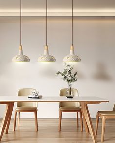 a dining room table with four chairs and a vase on the table next to it