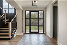 an empty entryway with stairs and glass doors leading to the front door is pictured in this image