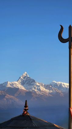 a tall wooden pole sitting next to a snow covered mountain range on a sunny day