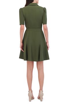 the back view of a woman wearing a green dress with short sleeves and pleaed skirt