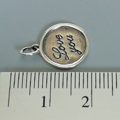 ▪︎ ONE sterling silver round charm with LOVE YOU inscribed on it. ▪︎ Size: 13 x 15 mm ( 17mm with hoop) Weight: 1.3 gm ▪︎ This is a multi functional charm and can be used with neck chains, ear hoops, bracelets, anklets, key chains etc. ▪︎ This pendant is handmade with hypoallergenic sterling silver, and is nickel free. Comes with a 925 mark for authenticity. ▪︎ Please note: Price listed is for ONE charm. This pendant comes WITHOUT the chain, however, you can add a snake neck chain, bracelet chai Inspirational Charms Jewelry For Anniversary, Inspirational Silver Jewelry For Birthday, Meaningful Hand Stamped Sterling Silver Charm Necklaces, Meaningful Hand Stamped Sterling Silver Charm Necklace, Gift Charm Necklace With Stamped 925 Pendant, Stamped 925 Pendant Charm Necklace As Gift, Stamped 925 Charm Pendant Necklace For Gift, Stamped 925 Silver Pendant Charm Necklace For Gift, Silver Hand Stamped Meaningful Charm Necklace