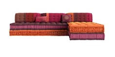 an orange and purple couch sitting on top of a white floor next to a pillow