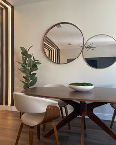 a dining room table with two mirrors on the wall