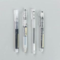 three pens are lined up next to each other on a white surface, one is black and the other is silver