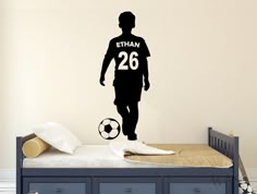 a bedroom with a bed, dresser and wall sticker depicting a man in soccer uniform