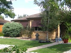 a house with landscaping in front of it and trees around the back yard on either side