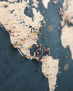 a map with pins all over it and the world on top of it's surface