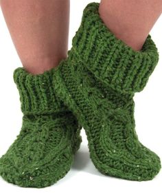 the legs of a person wearing green knitted socks and slippers with their feet up