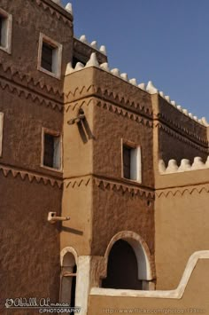 an adobe building with arched doorways and arches on the side, against a blue sky