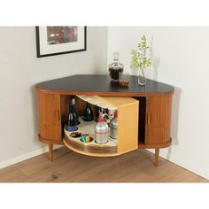 a wooden cabinet with bottles and glasses on it's side shelf in a room