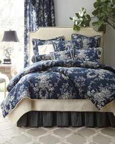 a blue and white comforter set with flowers on it in front of a window