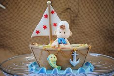 there is a cake that looks like a boat with a baby on it and fish