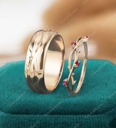 two wedding rings sitting on top of a blue towel next to each other with green stones