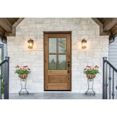 two flower pots on the front porch of a white brick house with wood trimming