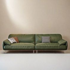 a green leather couch sitting on top of a white floor next to a light brown wall