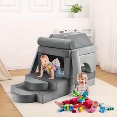 two toddlers playing in a play house made out of foam blocks on the floor