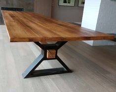 a wooden table sitting on top of a hard wood floor next to a white brick wall