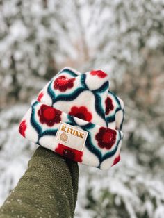 a person's hand wearing a hat with red, white and blue flowers on it