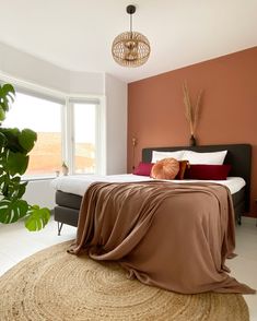 a bedroom with a large bed covered in a brown blanket and throw pillows on top of it